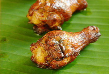 grilled chicken drum with black soy sauce on banana leaf