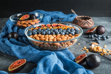 Breakfast with muesli, berries, figs and nuts on dark table