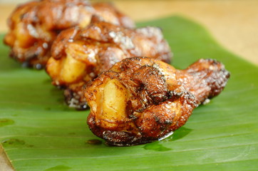 roasted chicken drum with black soy sauce on banana leaf