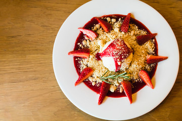 Ice cream with strawberry and cookie crumble on white dish