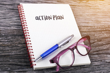 Note with action plan on the wooden background.