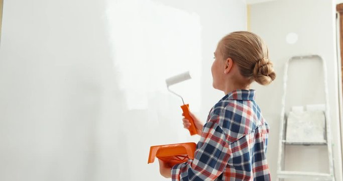 Cheerful girl 9 years old paints wall