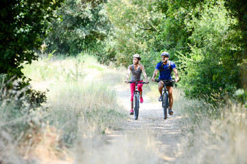 Fototapeta premium happy young couple riding bicycle in countryside during summer