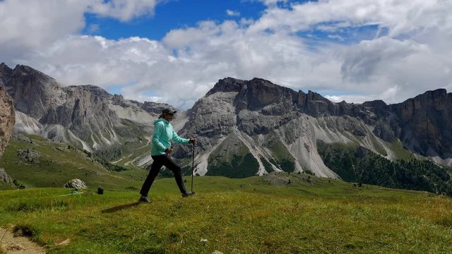 Woman hikes through a high-mountain meadow in Alps