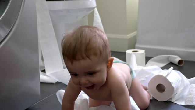 Toddler ripping up toilet paper in bathroom