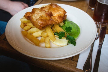 A traditional British plate of fish and chips with mushy peas on a diner table