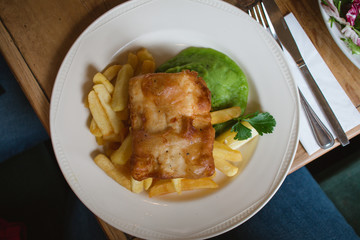 A traditional British plate of fish and chips with mushy peas on a diner table
