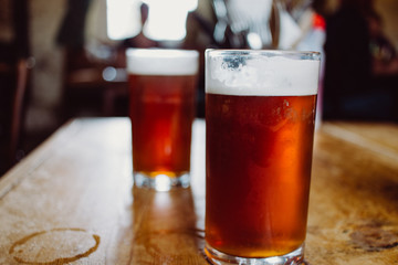 An english ale bitter beer pint on a wooden table in a pub in UK - obrazy, fototapety, plakaty
