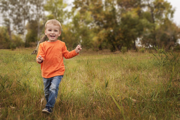 Little boy running in colorful autumn park, copyspace