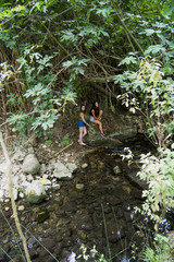 Two beautiful women in nature on the bank of a mountain river