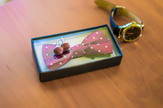 Groom's morning. Classic wedding men's accessories - watches, color bow and cufflinks on wooden table. Top view