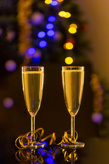 Two glasses of champagne on the table and blurred  decorated Christmas tree on background