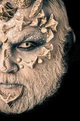 Man with dragon skin and grey beard, half face