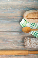 Many mixed breads and rolls of baked bread on wooden table background.