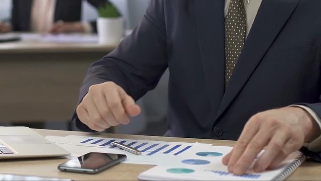 Financial director analyzing two charts and making notes, businessman at work