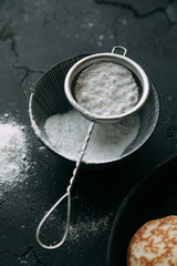 The process of cooking pancakes on a black background and set of ingredients