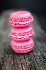 Delicious macarons raspberry flavored with fresh raspberries and a sprig of mint presented on a wooden shelf