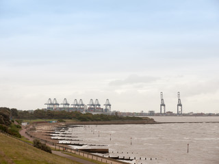 Fototapeta na wymiar sea industry cargo and shipping cranes in the distance beach groynes Harwich Port