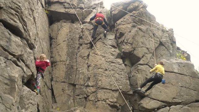 Children practice rock climbing. Children climb on a vertical rock