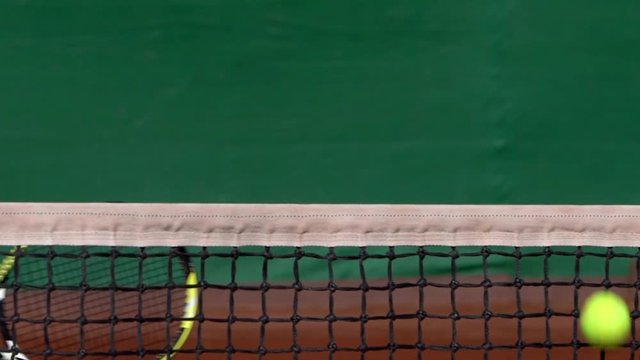 A tennis player hitting a backhand volley in slow motion by the net.