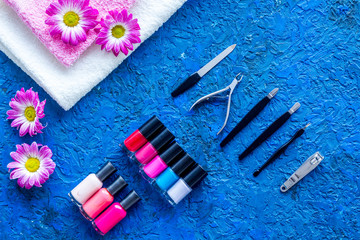 Manicure in beauty salon. Tools for manicure, nail polishes and towels on blue desk top view