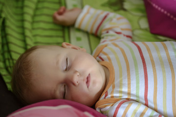 Little cute baby sleeps on a large bed with a serene sleep