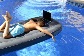 El niño esta en la piscina con su ordenador portatil