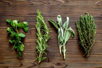 making spices with fresh herbs and greenery for cooking wooden kitchen table background top view