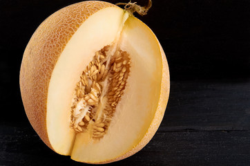 Fresh sweet yellow melon sliced on wooden black background. Raw organic melon isolated on wooden dark surface close up. Side view