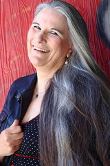 Eine lachende ältere Frau mit langen grauen Haaren