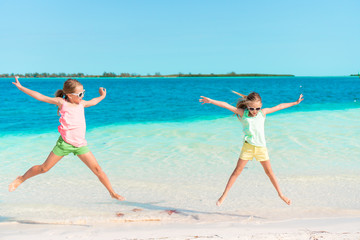 Adorable little girls having fun on the beach full of starfish on the sand