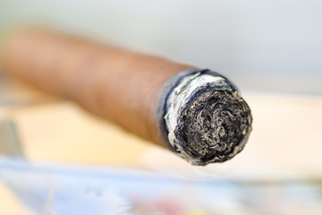 Close-up photo of a burning cigar in a glass ashtray