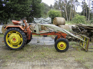 An old yellow red agricultural tractor on a farm