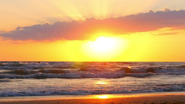 Beautiful sunset at the beach, waves rolling and seagulls are flying around.
