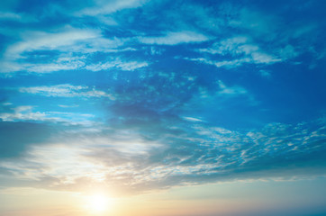 Gently-blue sky, clouds and sunset over the horizon.
