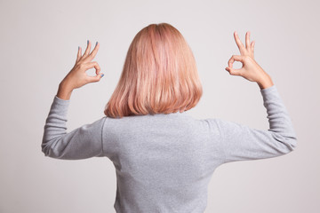 Back view of Asian woman show double OK hand sign.