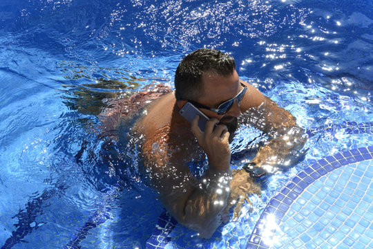El hombre esta en la piscina hablando por telefono