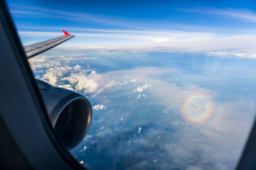 Wing of an airplane with the plane's shadow and a circular rainbow