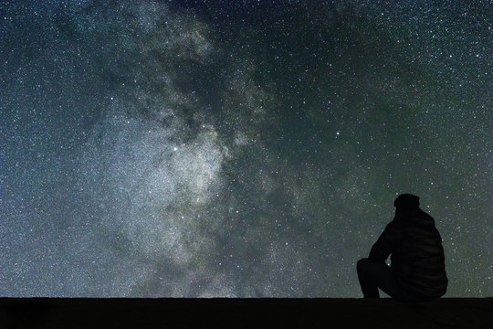 Milky Way. Night sky with stars and silhouette alone man looking at starry sky.