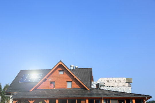 Dach drewnianego budynku z solarami fotowoltanicznymi i systemem wentylacji.