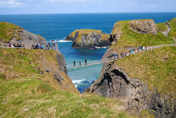 Ballintoy, United Kingdom - May 2, 2016: Carrick-a-Rede Rope Bridge, a popular tourist destination in Northern Ireland. Tourists passing the bridge.