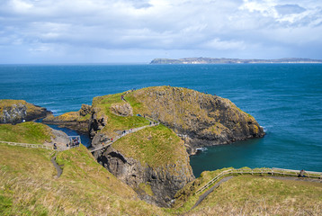 Ballintoy, United Kingdom - May 2, 2016: Carrick-a-Rede Rope Bridge, a popular tourist destination in Northern Ireland. Tourists passing the bridge.