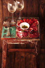 Cured Meat and vintage forks on textured Chalkboard and old wooden stool background