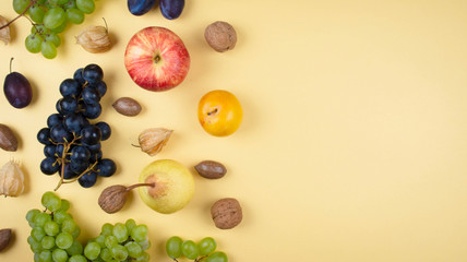Autumn fruits and nuts on yellow background.