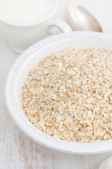 oatmeal in white bowl and a cup of milk on wooden background