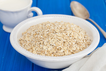 oatmeal in white bowl and a cup of milk on wooden background