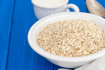 oatmeal in white bowl and a cup of milk on wooden background