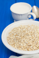 oatmeal in white bowl and a cup of milk on wooden background