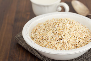 oatmeal in white bowl and a cup of milk on wooden background