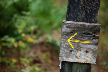Yellow arrow pointing left on a wooden post 